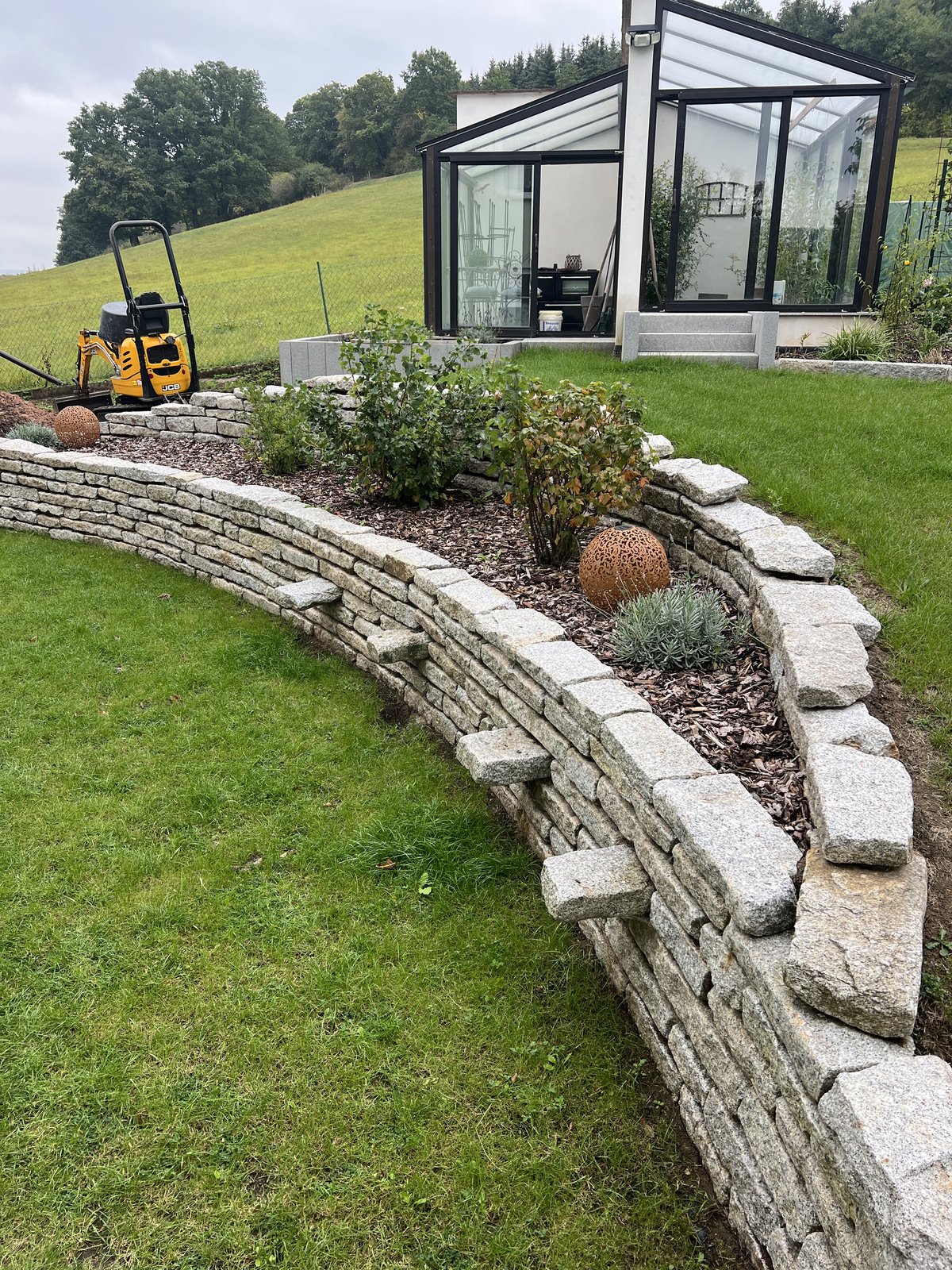 Geschwungene Mauer aus Granit-Kleinborde im Garten